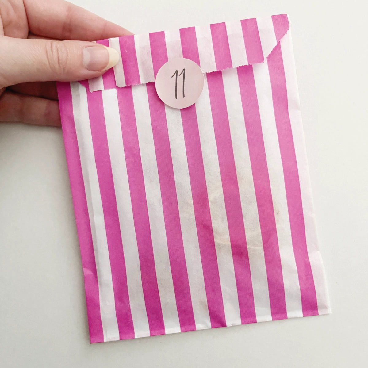 Day eleven's pink and white striped paper advent bag containing all of the materials for the day's project.