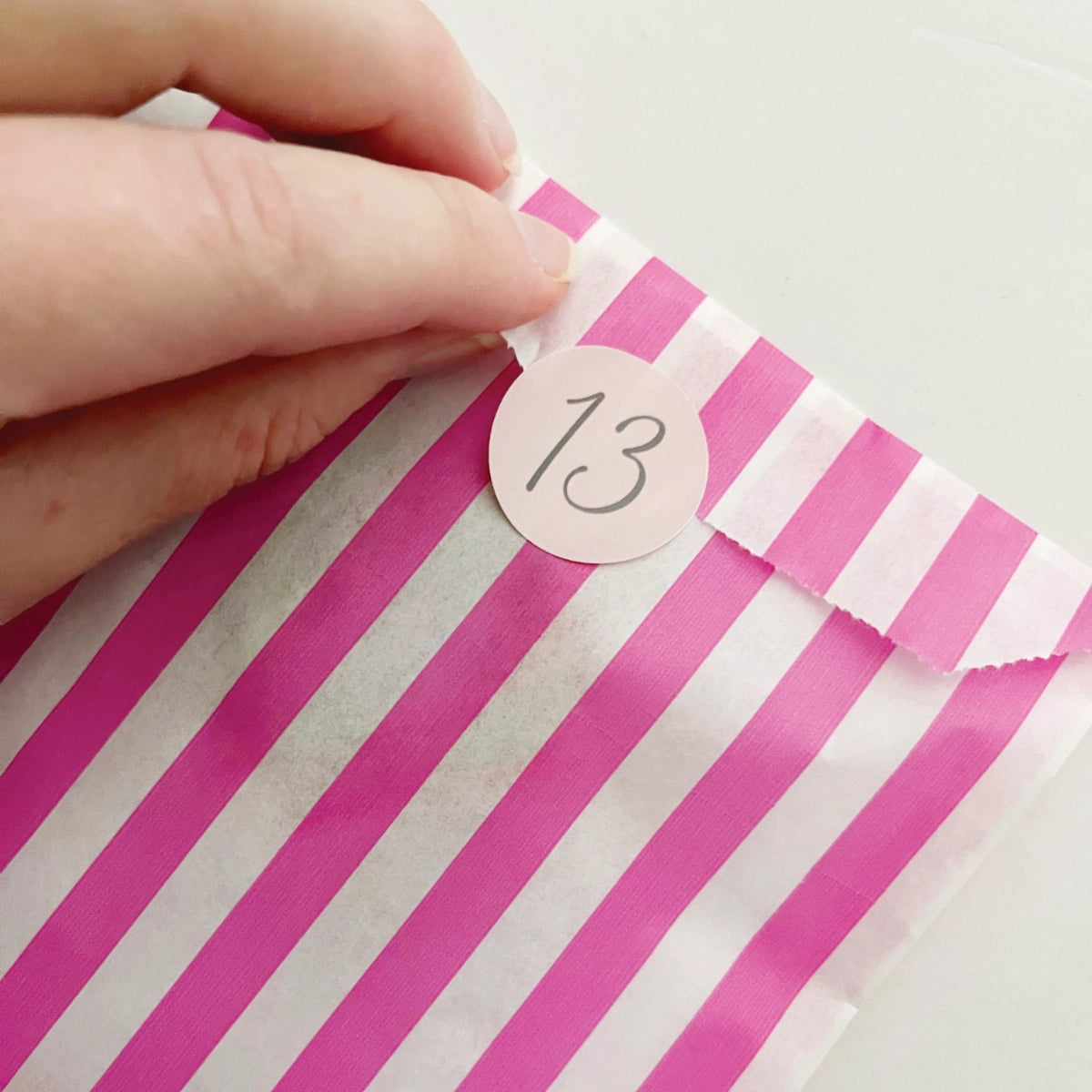 A hand opening the advent bag for day thirteen of the advent craft project.