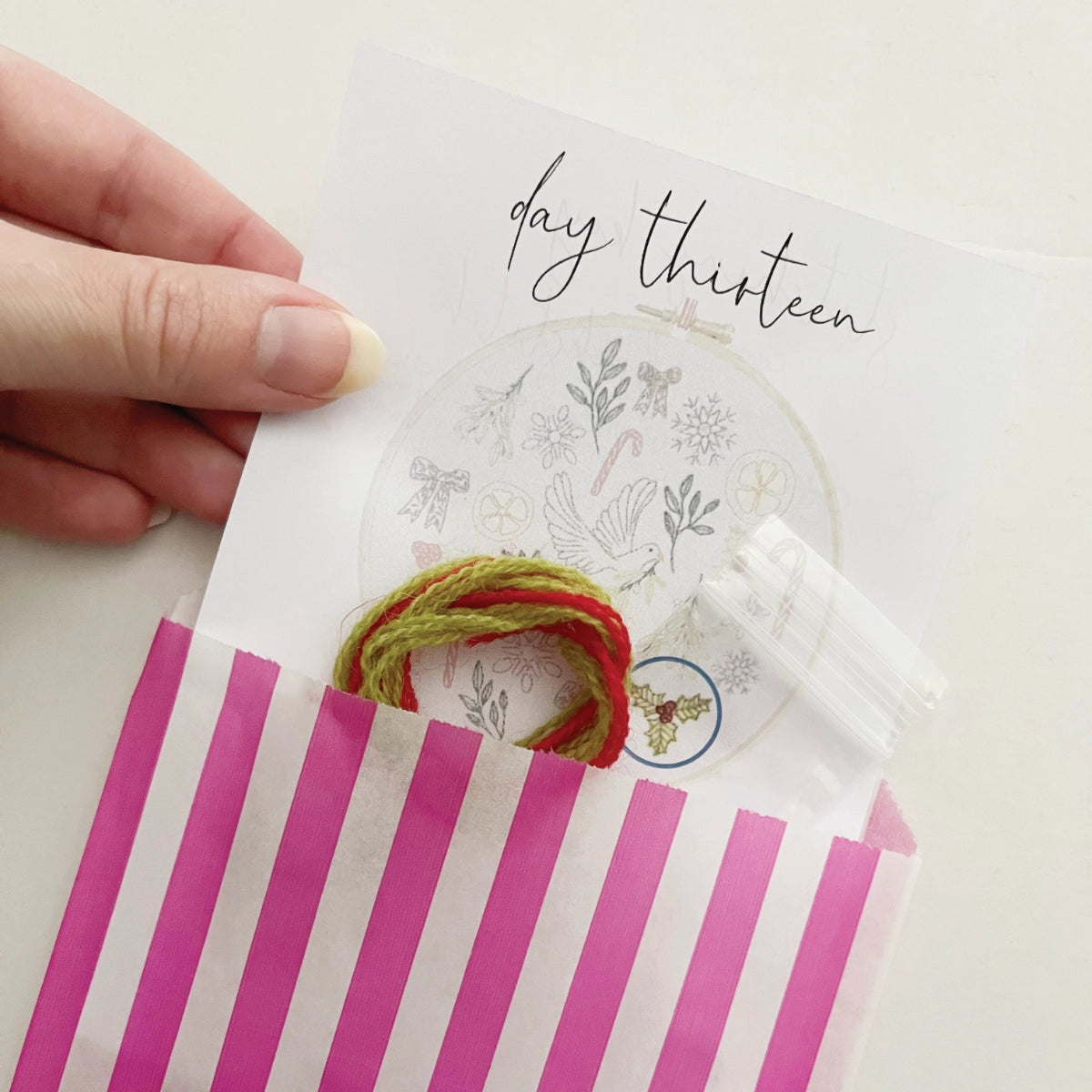 Daily materials from the Advent Calendar Embroidery Kit – threads, beads and instructions inside a paper bag for day thirteen's motif.