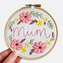 Load image into Gallery viewer, Mum Embroidery Kit - Kirsty Freeman Design. Close up of the finished embroidery kit for mum, with her name across the centre, stitched in backstitch. The botanical wreath combines satin stitch and backstitch to create florals, leaves and berries.
