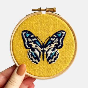 Butterfly Embroidery Kit - Kirsty Freeman Design. Close up photograph of the butterfly embroidery on yellow linen fabric, completed in satin stitch and with seed bead embellishment.
