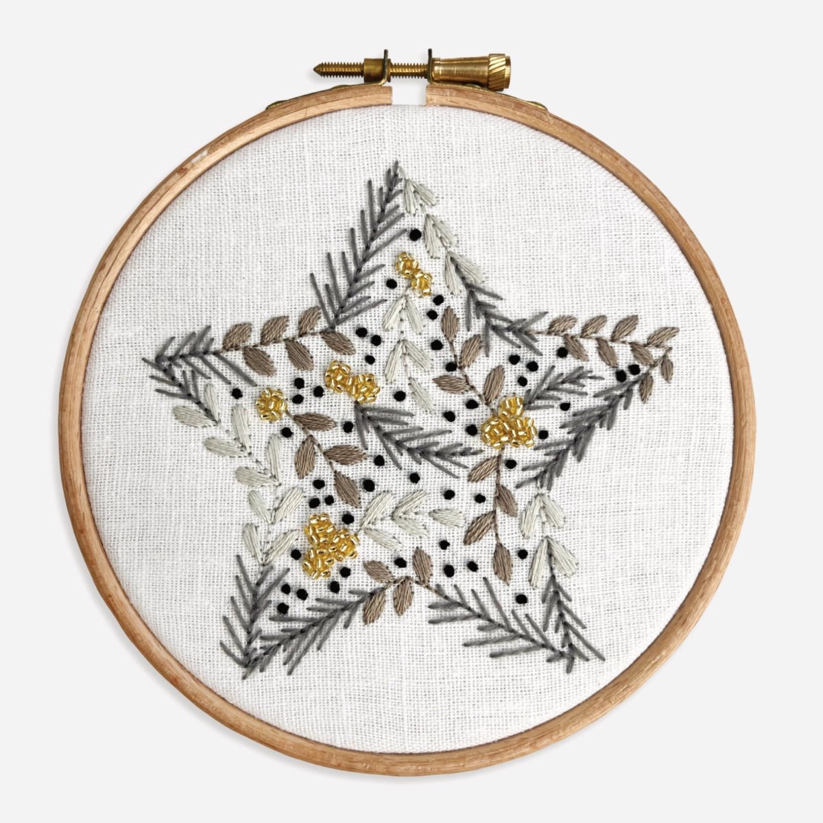 Close-up of completed Christmas Star Embroidery Kit showing botanical leaves, berries and gold seed beads in a star motif.