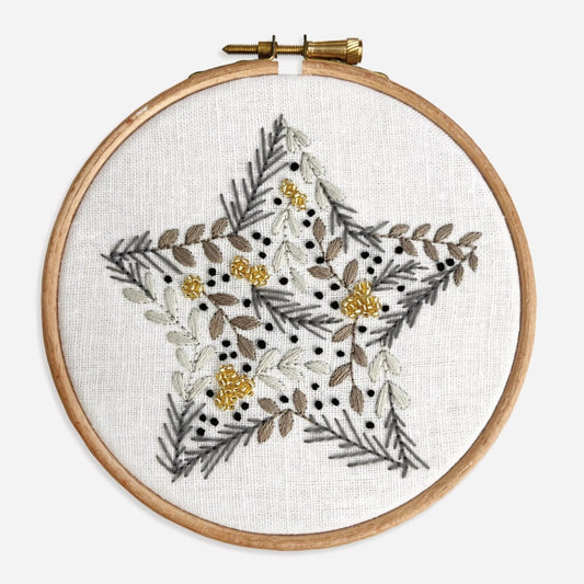 Close-up of completed Christmas Star Embroidery Kit showing botanical leaves, berries and gold seed beads in a star motif.
