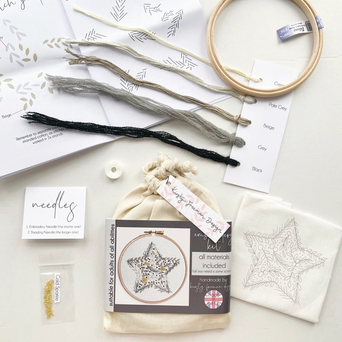 Christmas Star Embroidery Kit in giftable cotton bag packaging displayed with contents including fabric, hoop, thread, instructions, needles and beads for hand embroidery project.