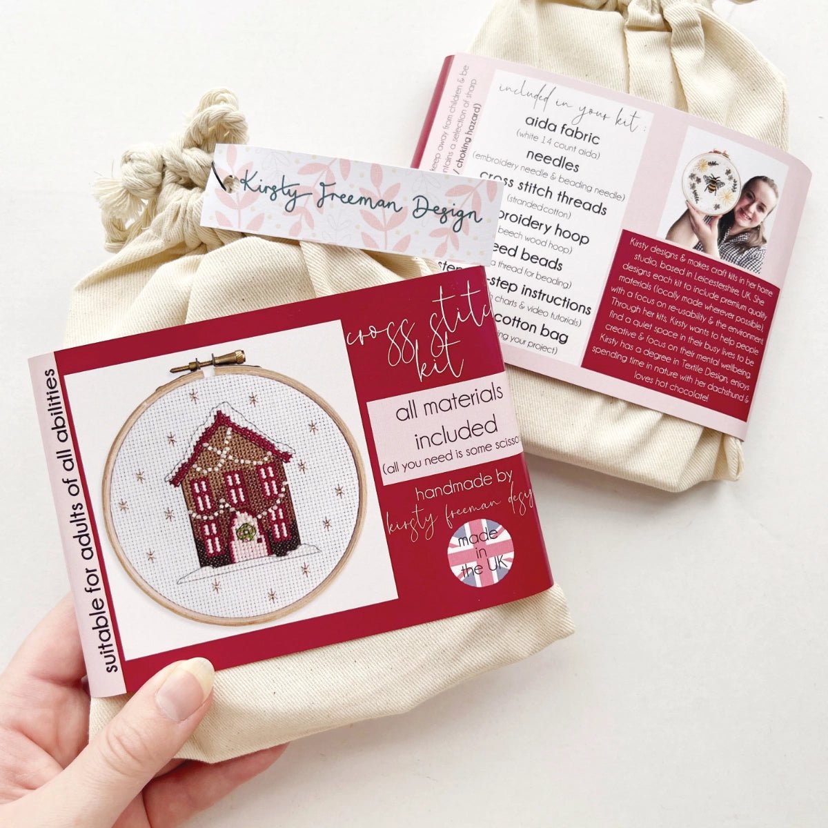 Front of Gingerbread House Cross Stitch Kit packaged in a cotton bag with coloured band showing festive house design.