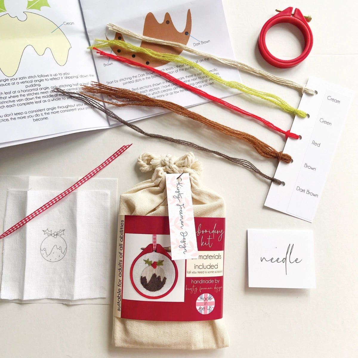 Christmas Pudding Embroidery Kit packaging with red hoop, fabric, threads, instructions, needle and ribbon to make festive DIY craft project.