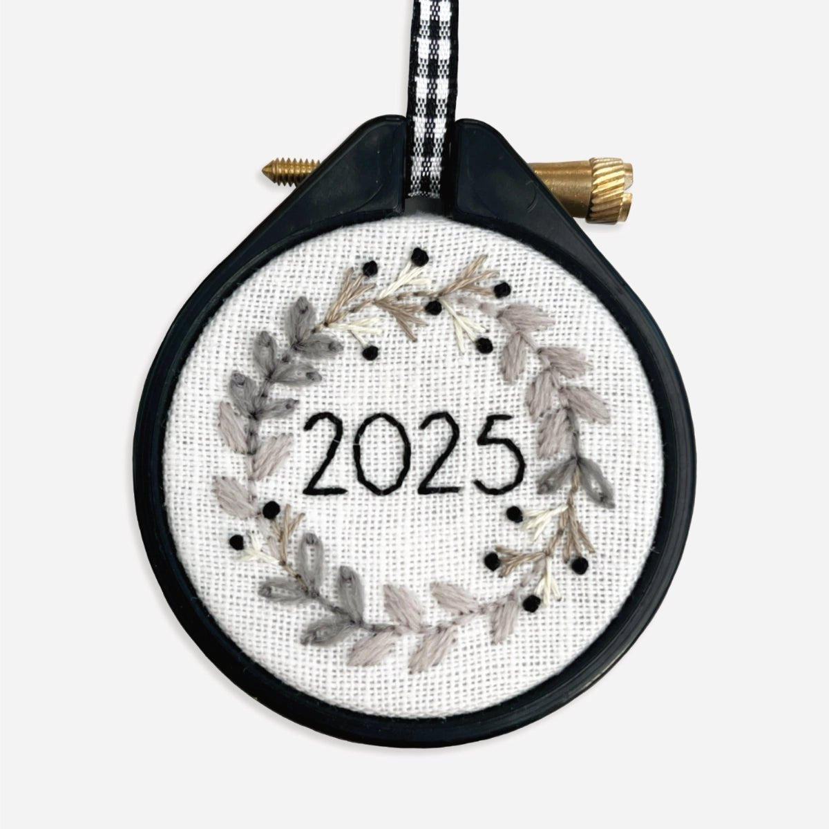 Close-up of finished monochrome wreath embroidery design stitched in cream, beige and black threads.