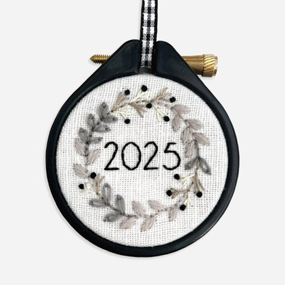 Close-up of finished monochrome wreath embroidery design stitched in cream, beige and black threads.