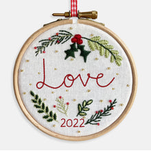 Load image into Gallery viewer, Christmas Decoration Kits - Kirsty Freeman Design. Close up, the word Love is stitched in red thread, onto white fabric, surrounded by Christmas foliage and gold beads.

