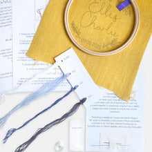 Load image into Gallery viewer, Personalised Baby Embroidery Kit - Kirsty Freeman Design. The contents of the mustard yellow name embroidery kit are: linen fabric, embroidery hoop, instructions, threads, beads and needles.
