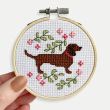 Load image into Gallery viewer, Dachshund Cross Stitch Kit - Kirsty Freeman Design. A close up of the cross stitch design, which depicts a sausage dog breed cross stitch pattern, surrounded by pink and green botanical stitches.
