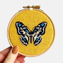 Load image into Gallery viewer, Butterfly Embroidery Kit - Kirsty Freeman Design. Close up photograph of the butterfly embroidery on yellow linen fabric, completed in satin stitch and with seed bead embellishment.
